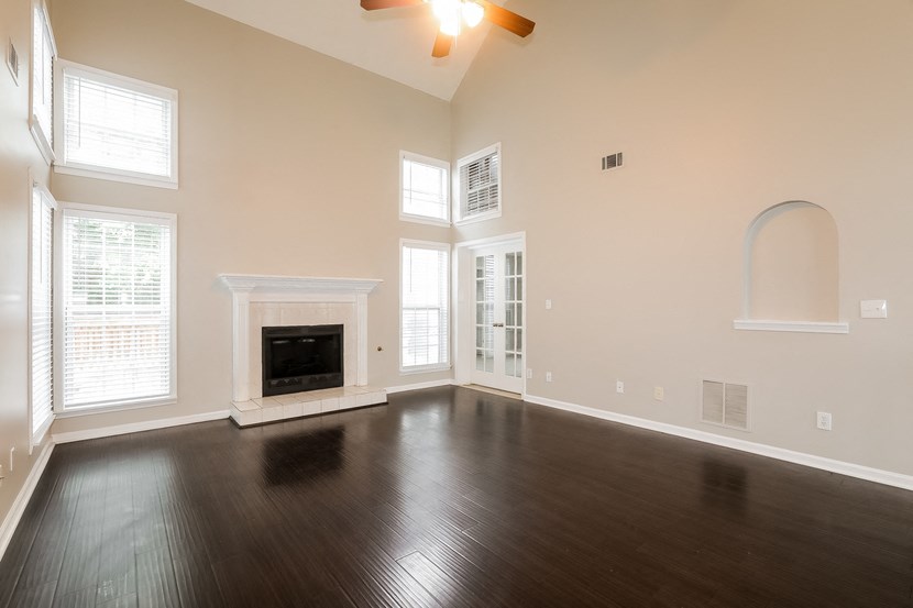 A spacious room with a fireplace and hardwood floors.
