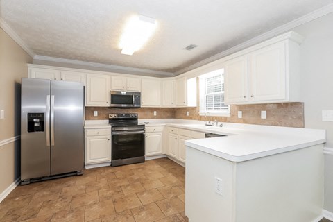 A kitchen with a refrigerator, oven, and microwave.