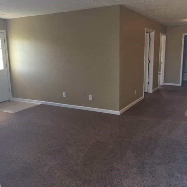 an empty living room with a carpeted floor