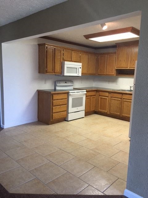 an empty kitchen with wooden cabinets and a white stove