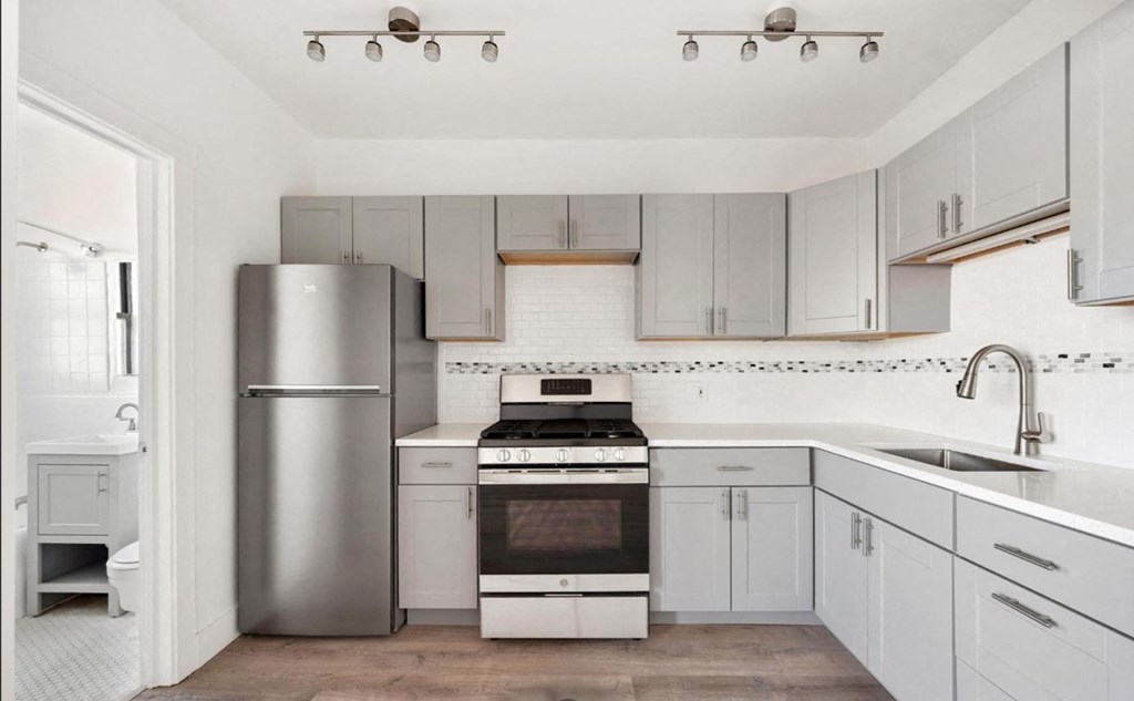 A modern kitchen with a stainless steel refrigerator, oven, and sink.