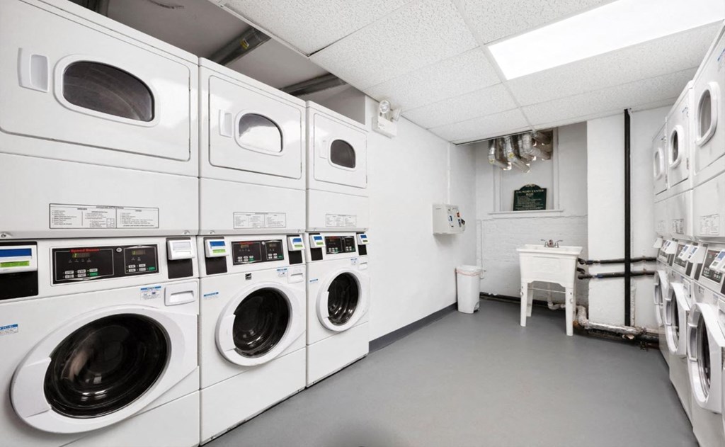 A row of white front load washing machines in a laundromat.