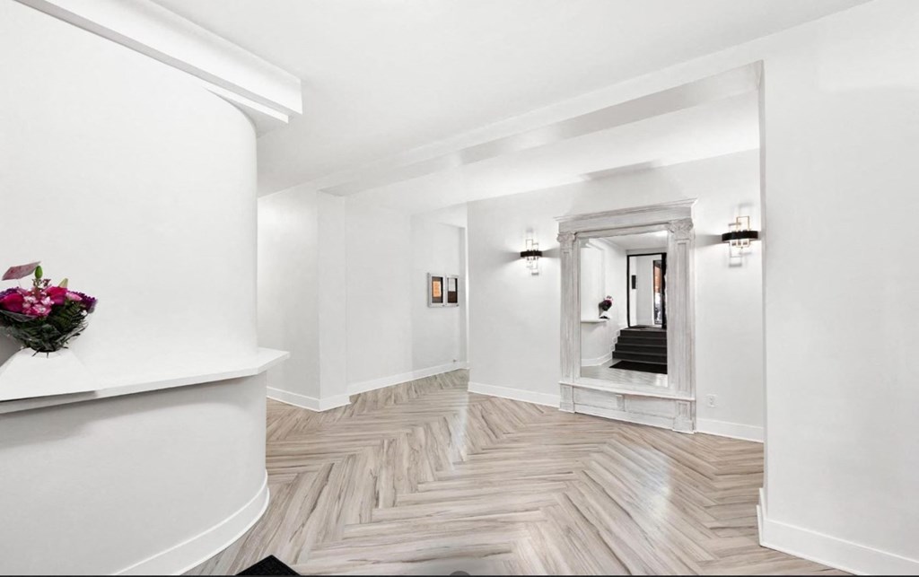 A hallway with a herringbone patterned floor and white walls.