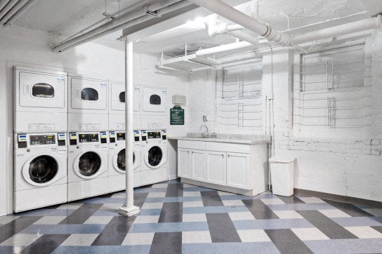an empty laundry room with white washing machines and a checkered floor