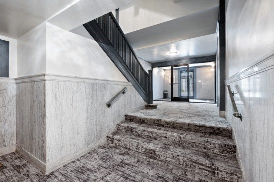 the lobby of a building with stairs and a carpeted floor