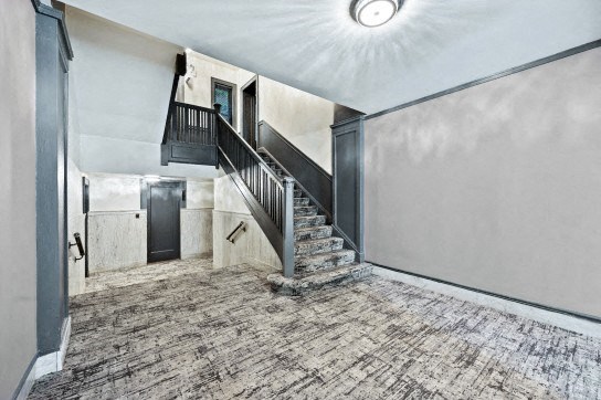 the entryway of a house with a staircase and a ceiling light