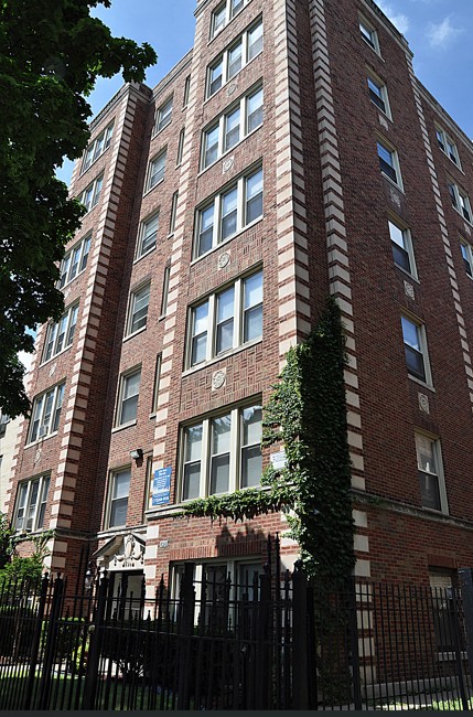 A tall red brick building with ivy growing on the side.