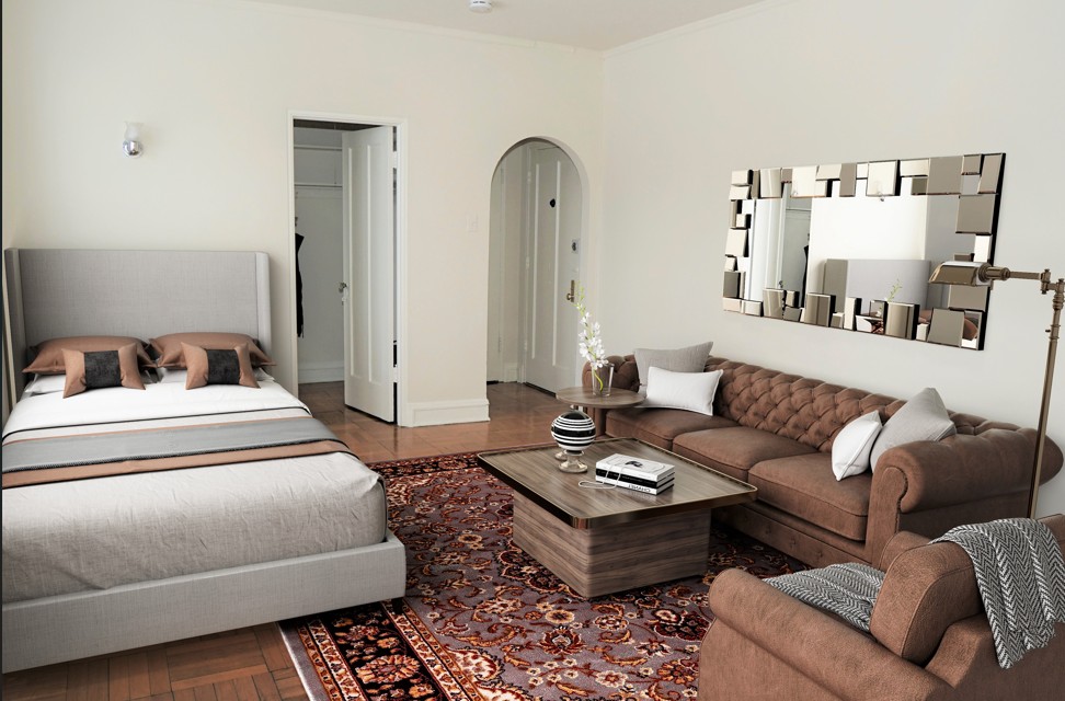 A bedroom with a bed, a couch, and a mirror on the wall.