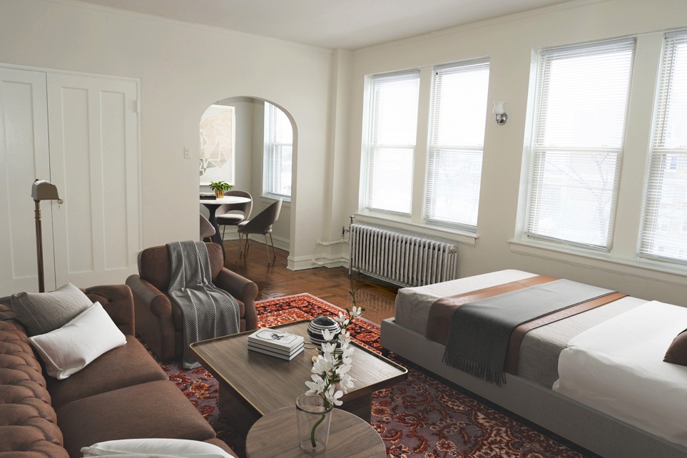 A living room with a brown couch and a coffee table with a vase of flowers on it.