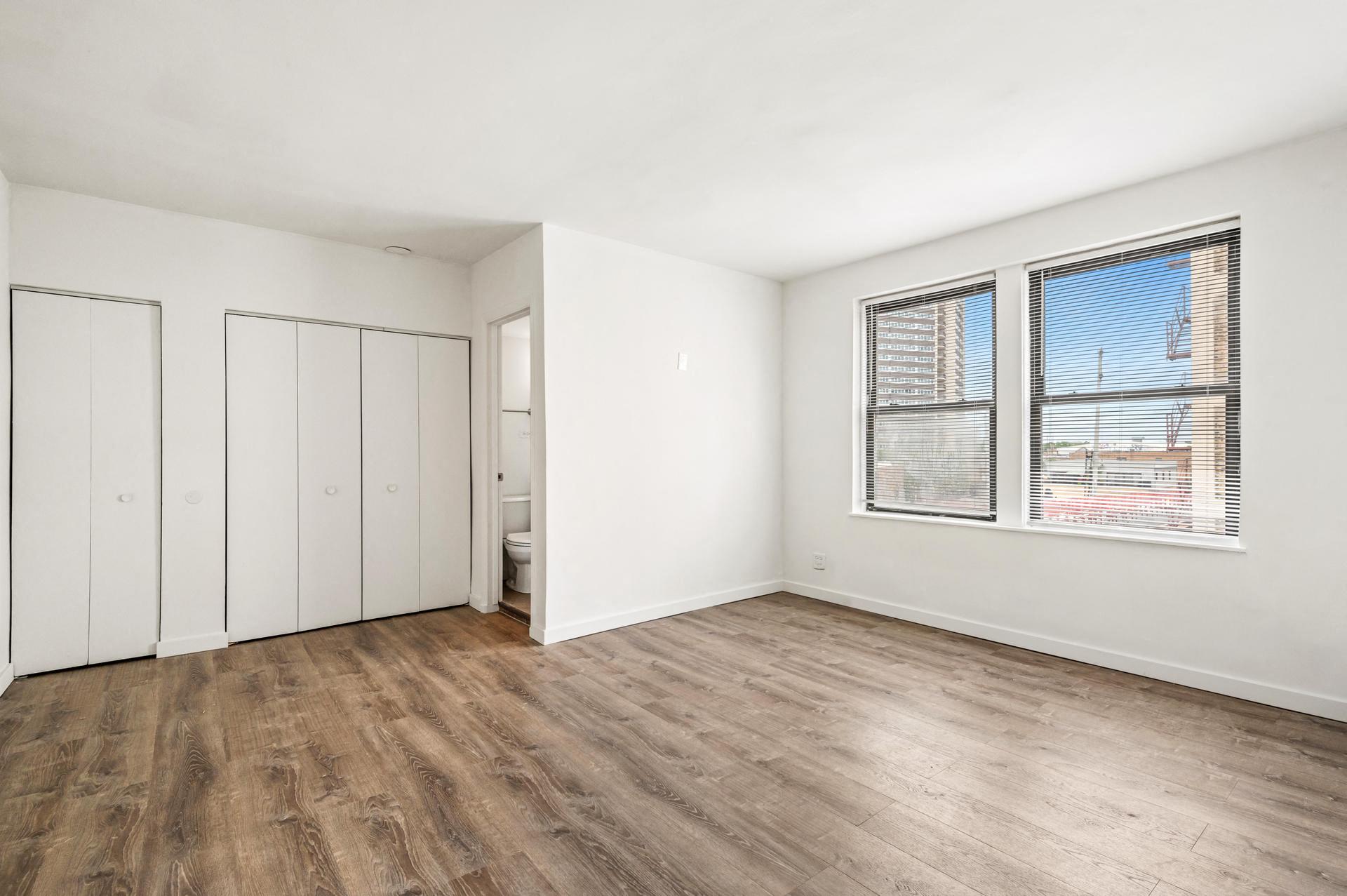 an empty bedroom with a window and a closet