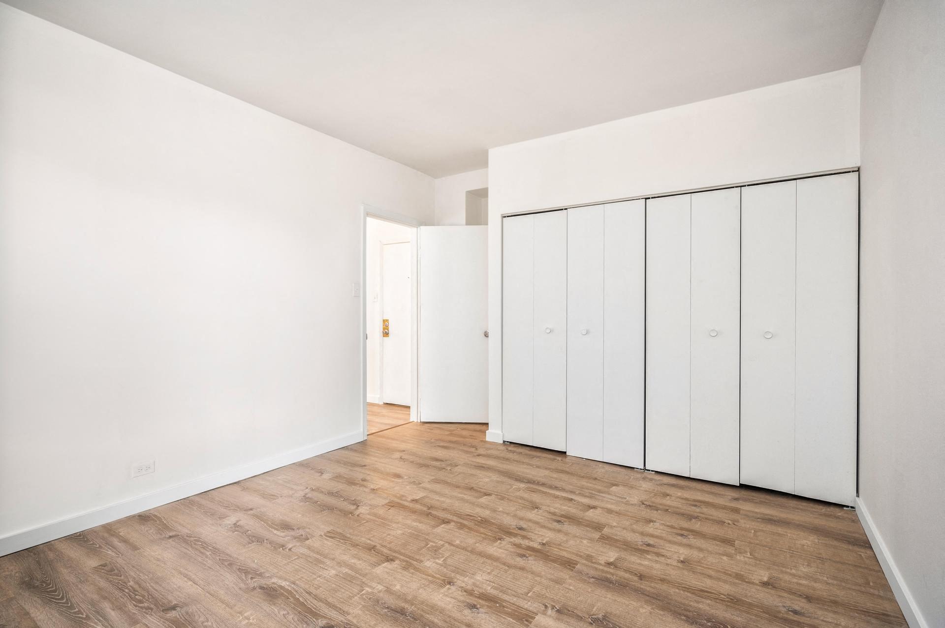 a bedroom with white walls and wood floors