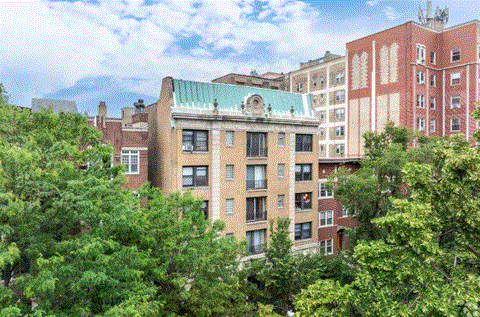 A building with a green roof is surrounded by trees.