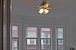 a large empty room with a ceiling fan and windows