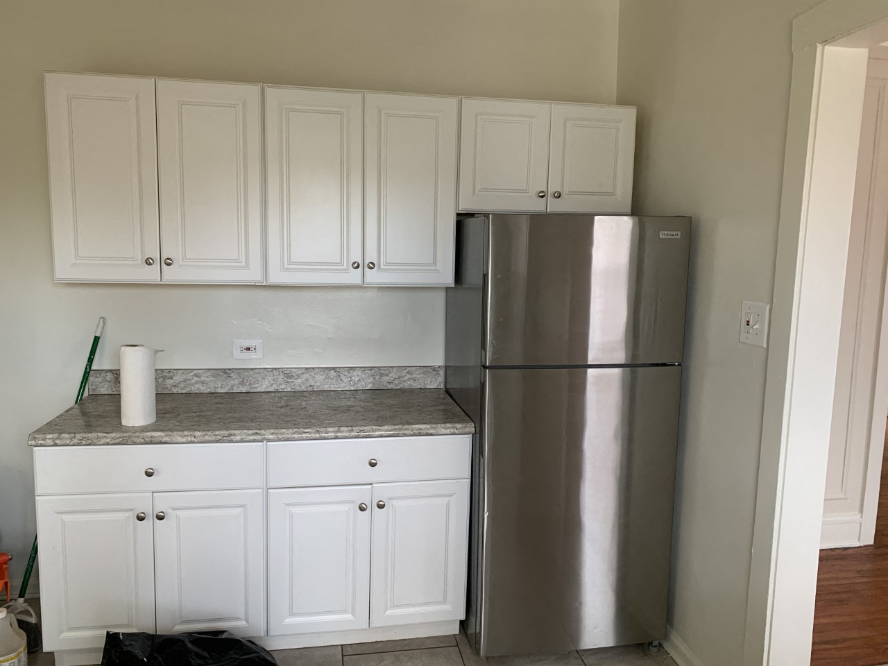 a kitchen with white cabinets and a stainless steel refrigerator