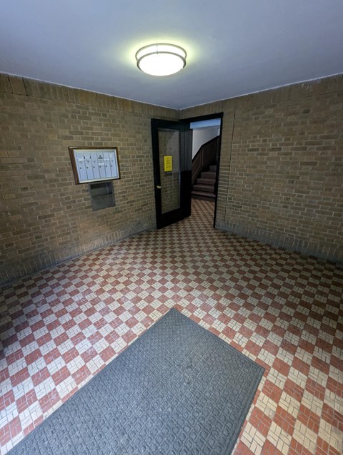 A hallway with a brick wall and a checkered floor.