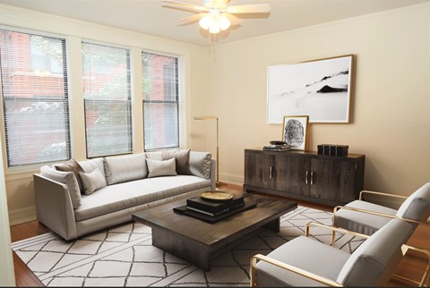 A living room with a grey couch, a coffee table, and a painting on the wall.