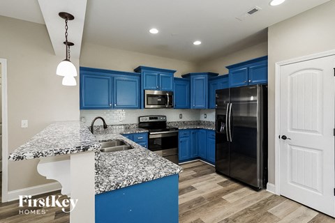 A kitchen with blue cabinets and a granite countertop.