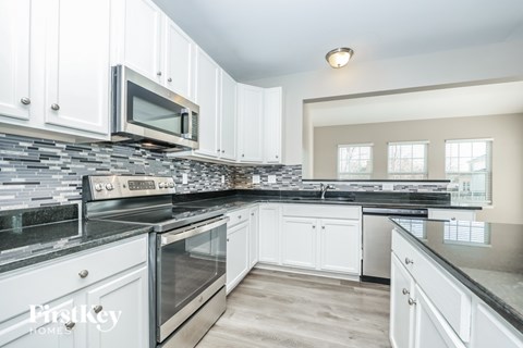 A kitchen with white cabinets and a stone backsplash.