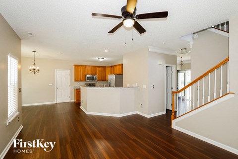 A spacious living room with wood floors and a ceiling fan.