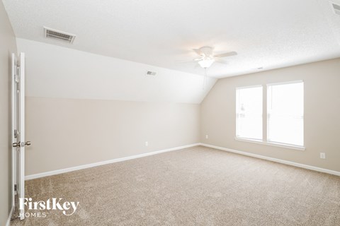 A spacious room with a carpeted floor and a ceiling fan.