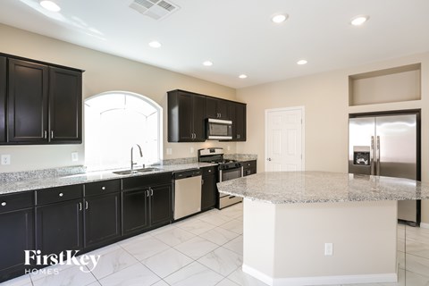 A kitchen with black cabinets and a granite countertop.