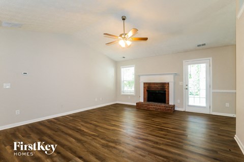 A spacious room with a fireplace and a ceiling fan.