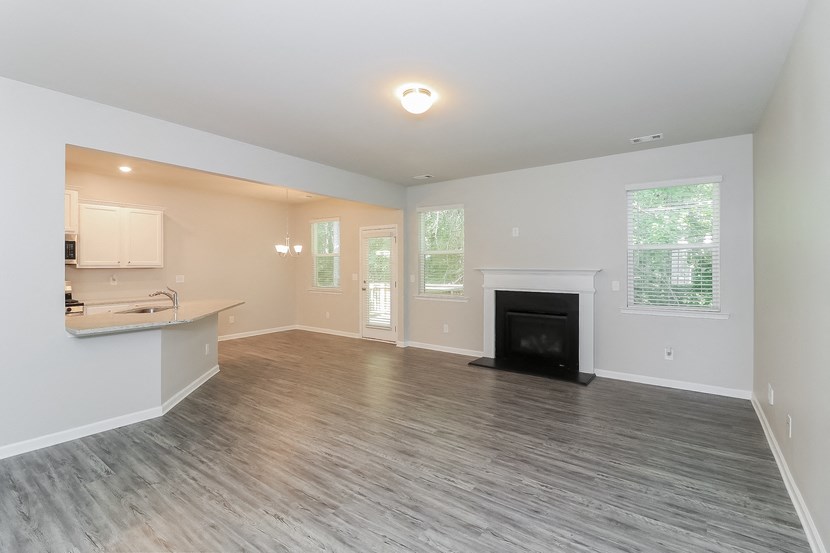 an empty living room with a fireplace and a kitchen
