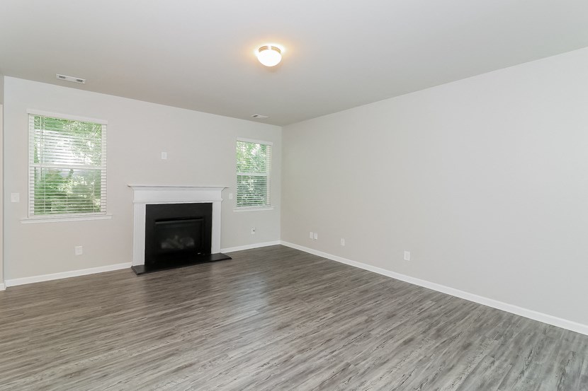 an empty living room with a fireplace and wooden floors