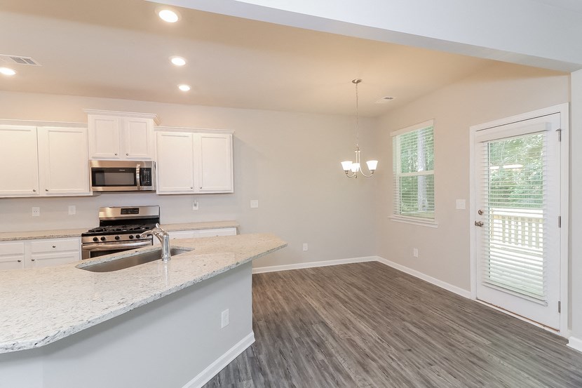 an empty kitchen and living room with white cabinets and a counter top