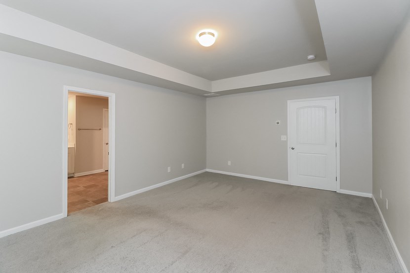 an empty living room with a white door and a carpeted floor