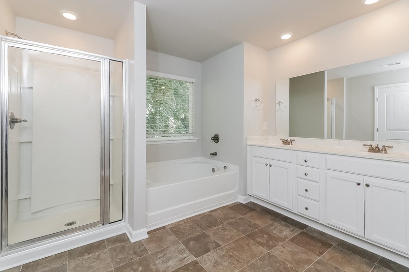 a bathroom with a tub and a shower and white cabinets