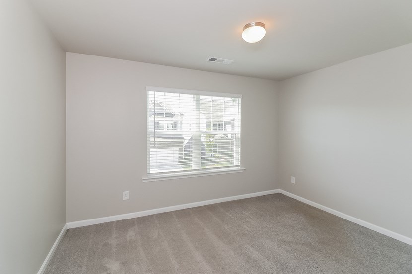 an empty bedroom with a large window and carpeting