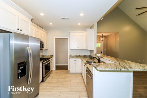 A kitchen with a stainless steel refrigerator and white cabinets.