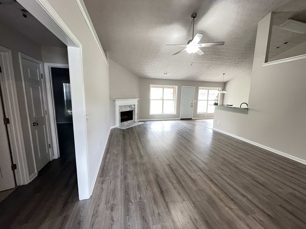 an empty living room with wooden floors and a ceiling fan