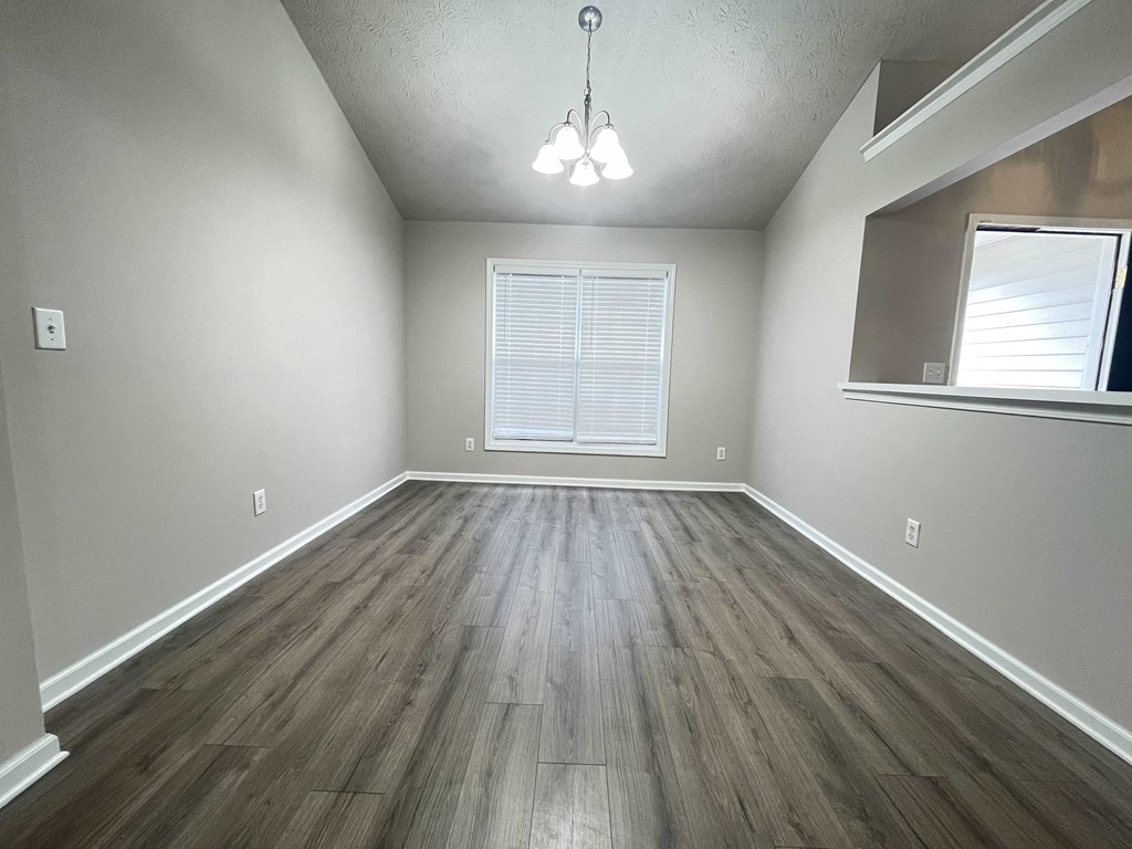 an empty living room with wood floors and a window