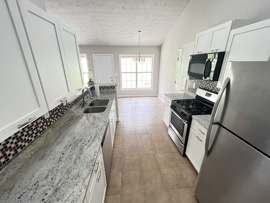 a large kitchen with white cabinets and stainless steel appliances