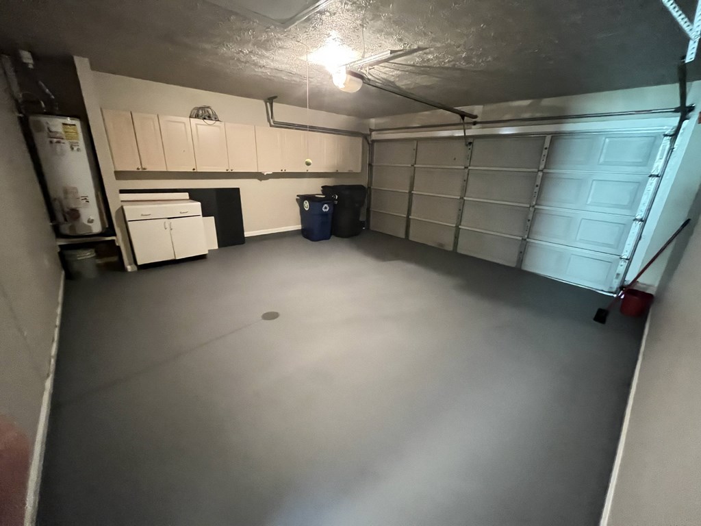 an empty garage with white cabinets and a refrigerator and a sink