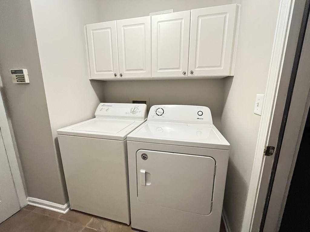 a laundry room with a washer and dryer and white cabinets