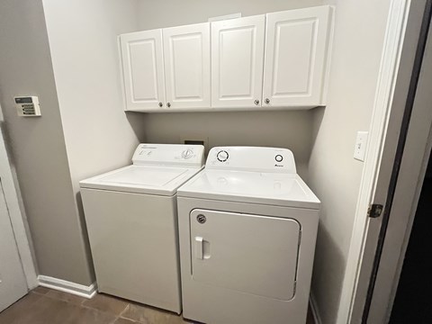 a laundry room with a washer and dryer and white cabinets