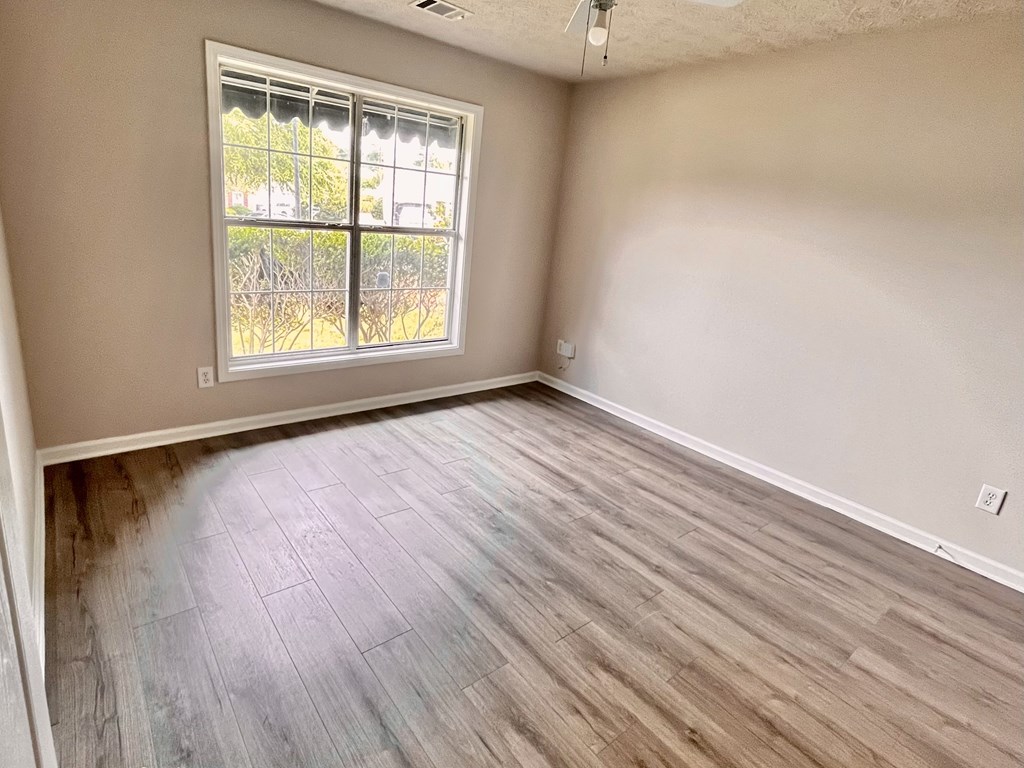 an empty living room with wood floors and a window