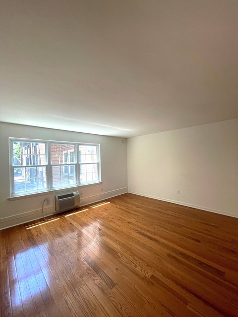 A room with a window and a wooden floor.