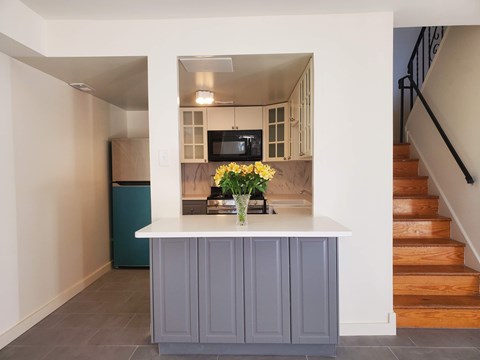 A kitchen with a white counter and a blue trash can.