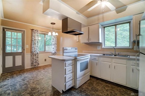 A kitchen with a white counter top and a window with curtains.