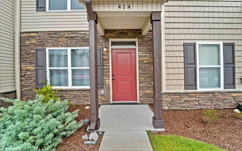 the front entrance to a home with a red door