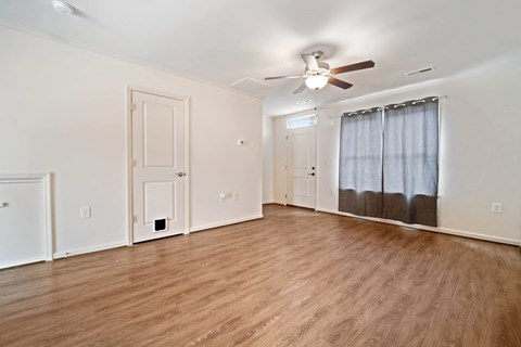 an empty living room with a ceiling fan and a closet