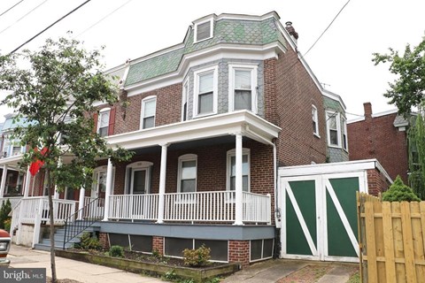 A red brick house with a green roof and white trim.