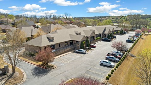 A parking lot in front of a building with cars parked.