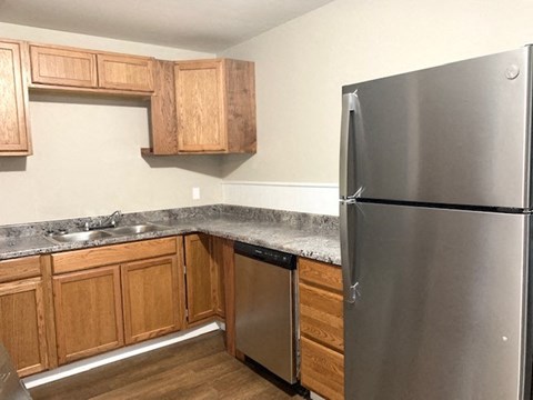 A kitchen with a stainless steel refrigerator and wooden cabinets.