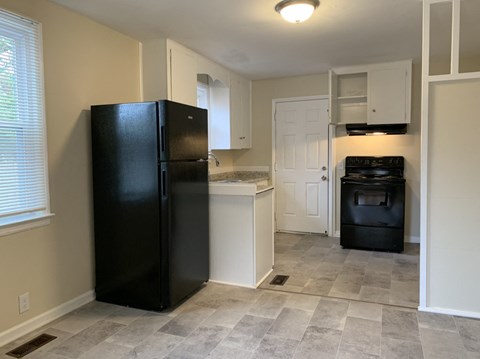 A black refrigerator in a kitchen with a black oven.