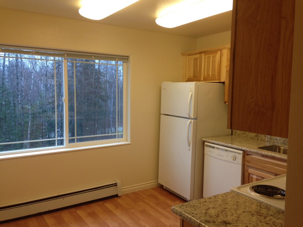 A kitchen with a white refrigerator and a window.